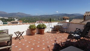 Eine Terrasse mit Blumentöpfen, einem Tisch und Stühlen.