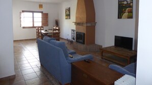 Ein Wohnzimmer mit Kamin, blauen Sofas, einem Holztisch und einem Fernseher.