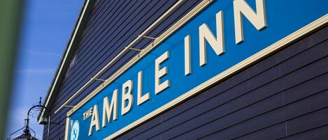 A sign for The Amble Inn with a nautical anchor logo.