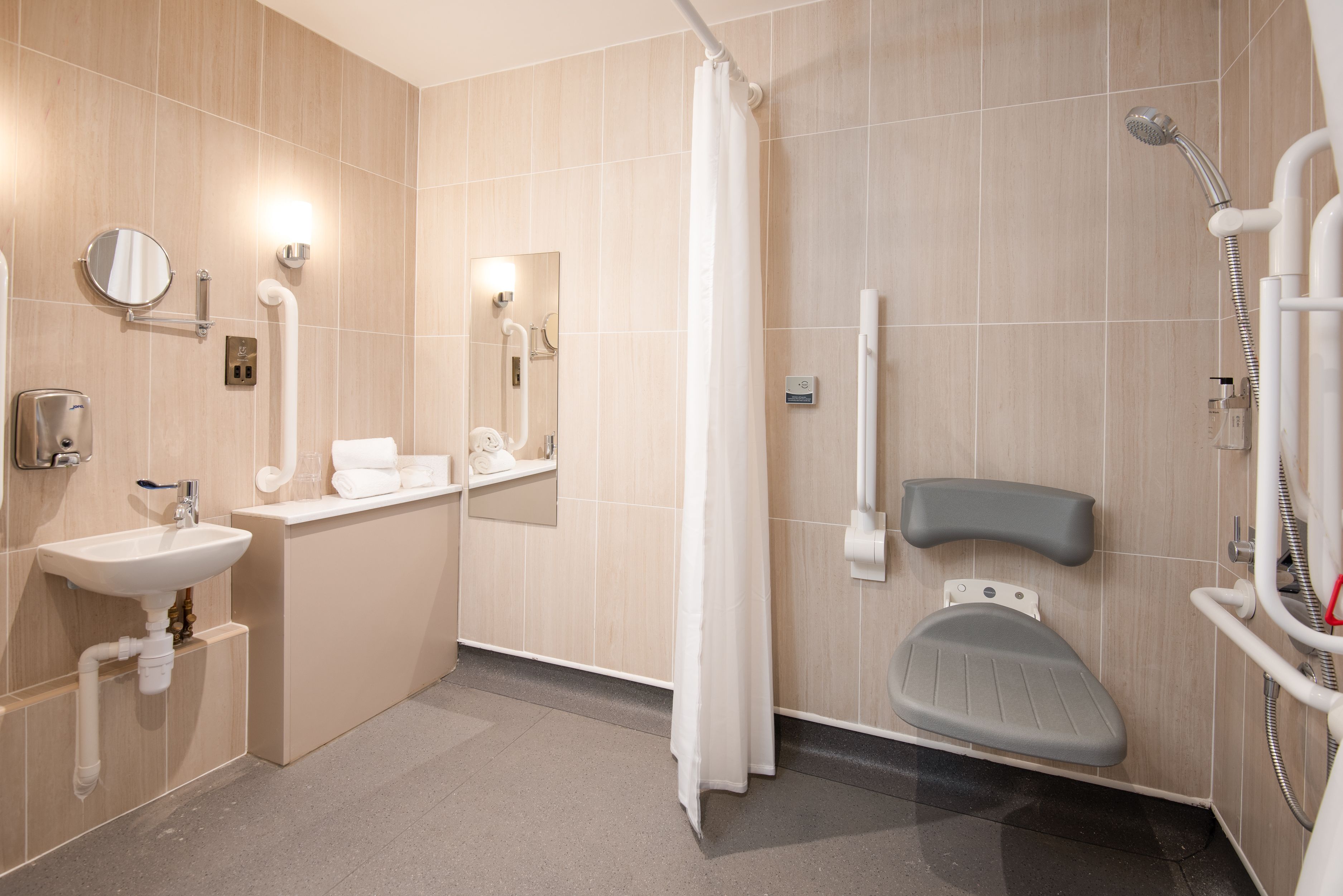 Een moderne badkamer met een wastafel, spiegel, toilet en douche.