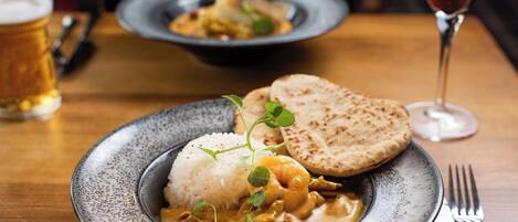 A plate of food with rice, a curry dish, and flatbread on a speckled ceramic plate.