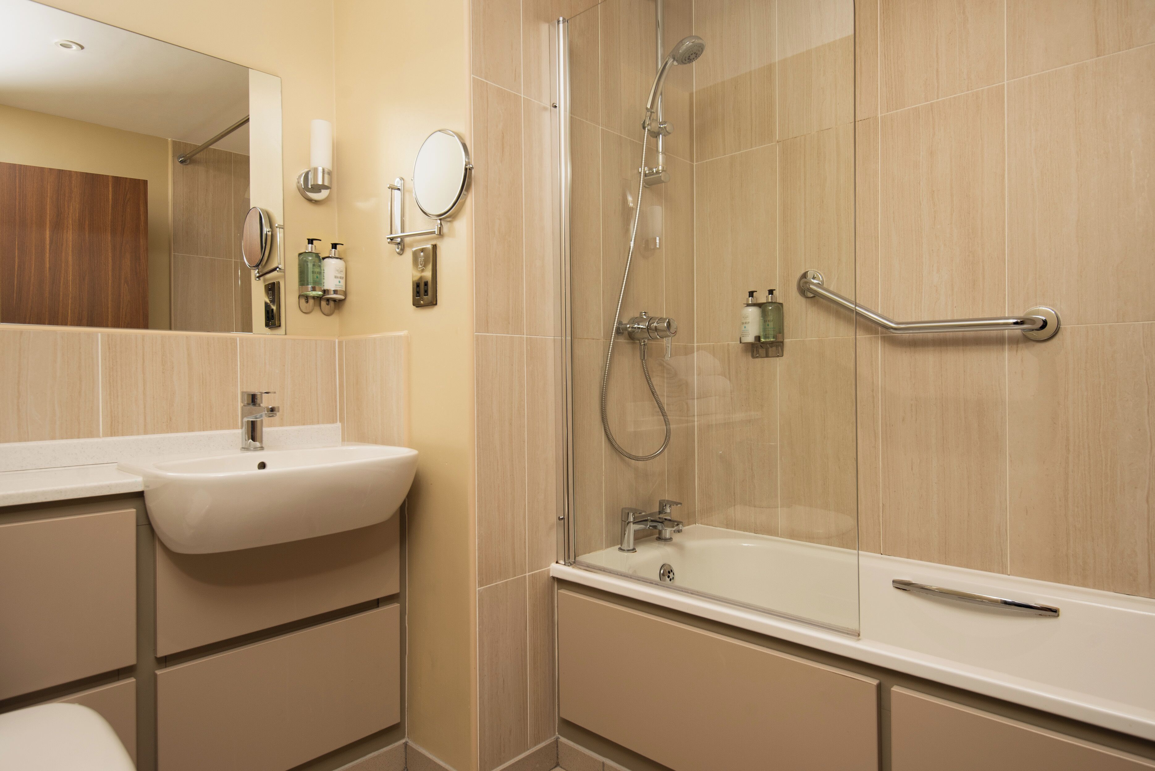 A modern bathroom with a sink, mirror, and shower.
