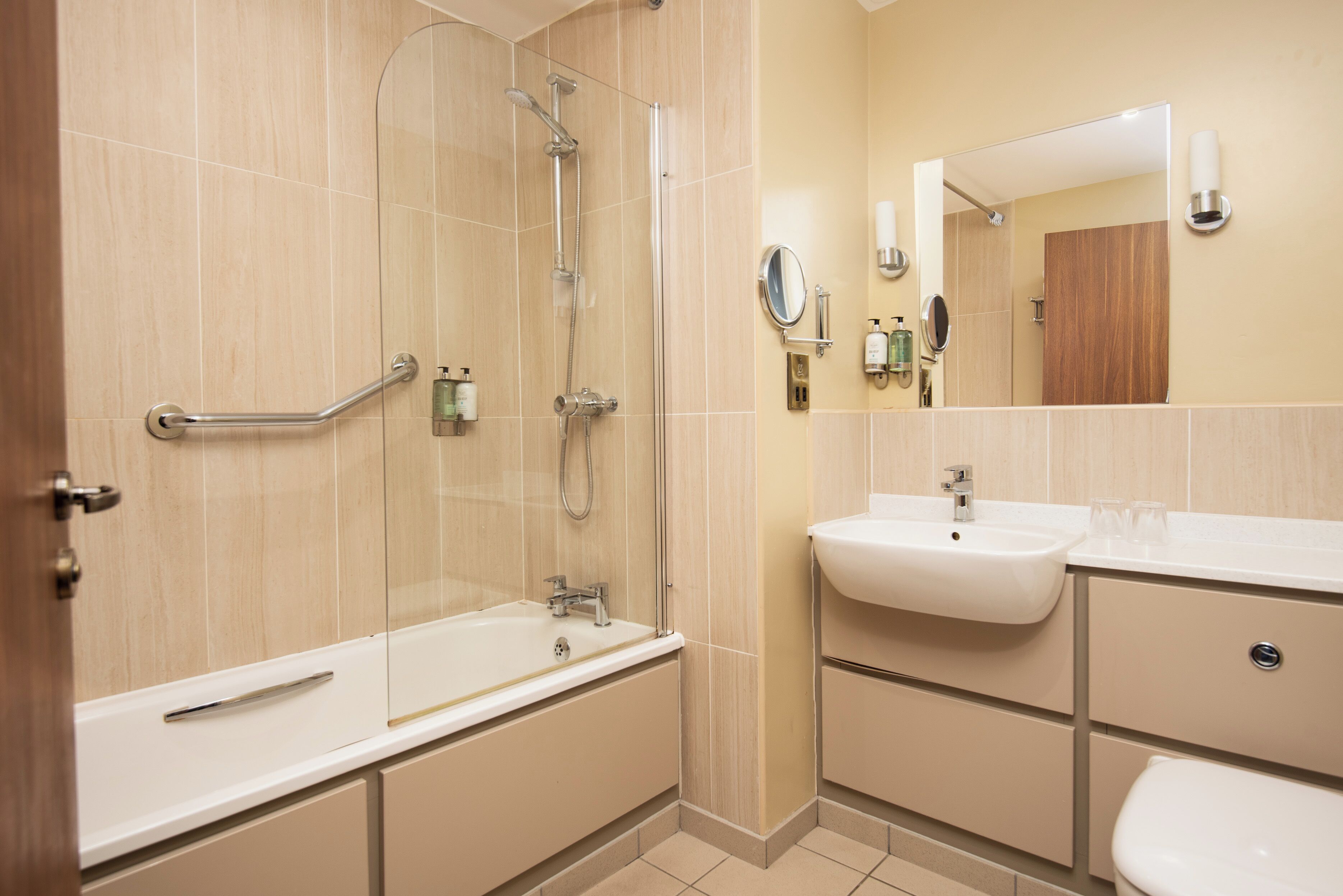 A modern bathroom with a bathtub, shower, and sink.