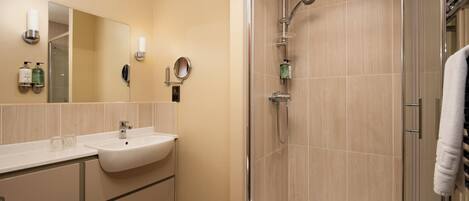 A modern bathroom with a sink, mirror, and shower.