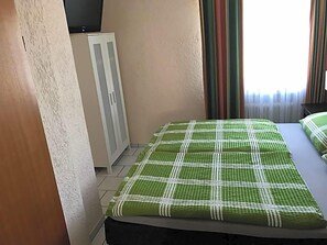 A room with a bed, a wardrobe, and a window with curtains.