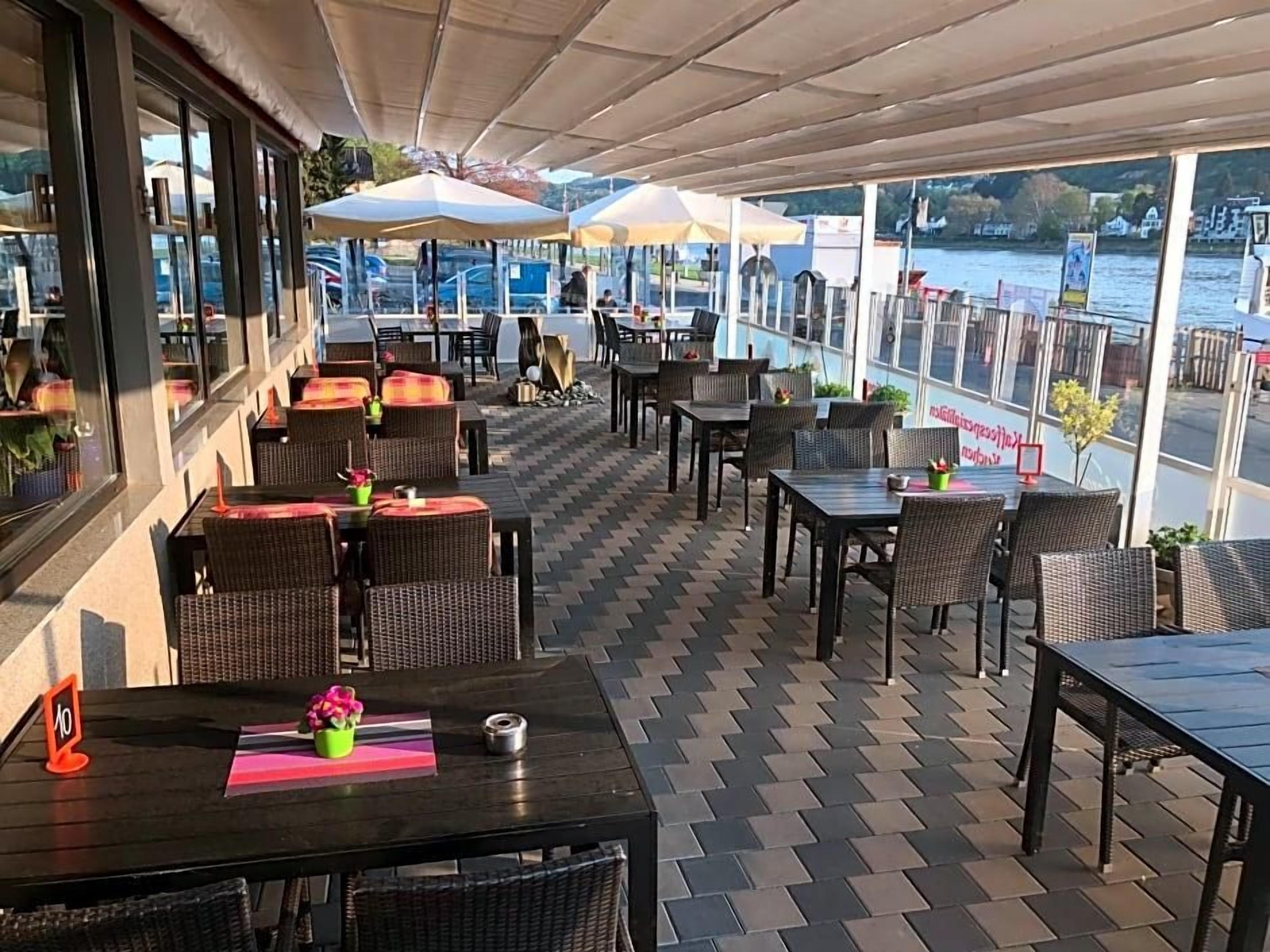 An outdoor seating area with tables and chairs, overlooking a body of water.