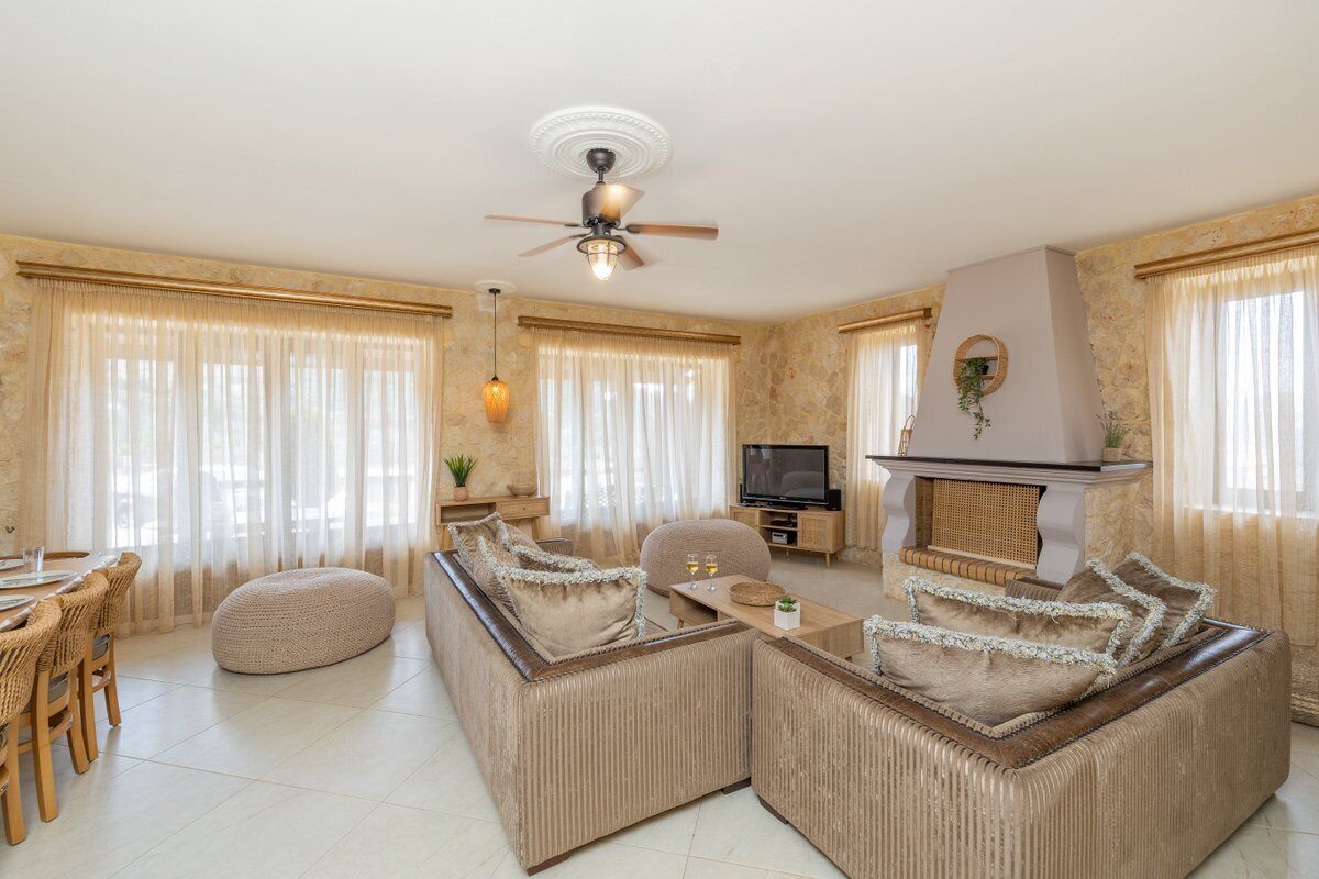 A spacious living room with a sofa set, a dining area, and a television.