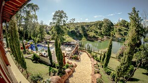 Vista de una zona ajardinada con piscina, mobiliario exterior y un estanque.