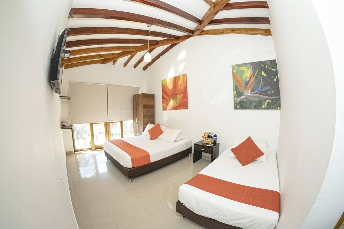 Habitación de hotel moderna con dos camas, vigas de madera en el techo, obras de arte en las paredes y un ventanal con vistas.