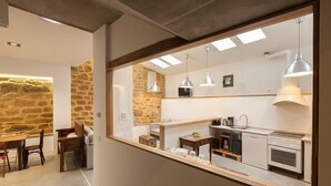 A modern kitchen with a stone wall, a dining area with a table and chairs, and pendant lighting.