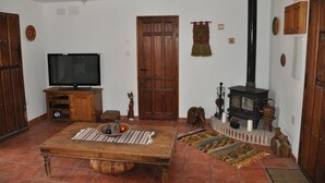 Un salon chaleureux avec une table en bois, un téléviseur, une cheminée et une porte de style traditionnel.