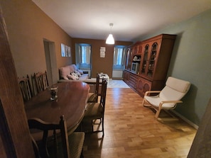 A dining area with a wooden table and chairs, a sofa, and a cabinet with glass doors. - Fully renovated tourist house for rent very cozy (Valga)