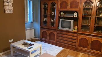 A living room with a wooden cabinet, a television, and a white table.