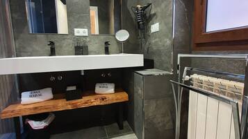 Un baño moderno con un espejo grande, dos lámparas colgantes, un perchero y un toallero.