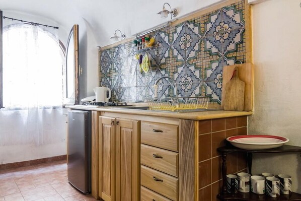 A kitchen with a tiled backsplash, wooden cabinets, a sink, and a stove.