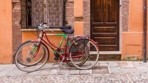Una bicicleta aparcada davant d'un edifici amb façana de pedra i porta de fusta.