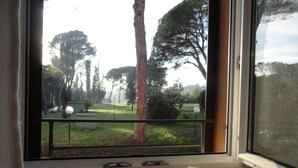 A window with a view of a park, a tree, and a book on a windowsill. - Hotel Sacro Cuore (Perugia)
