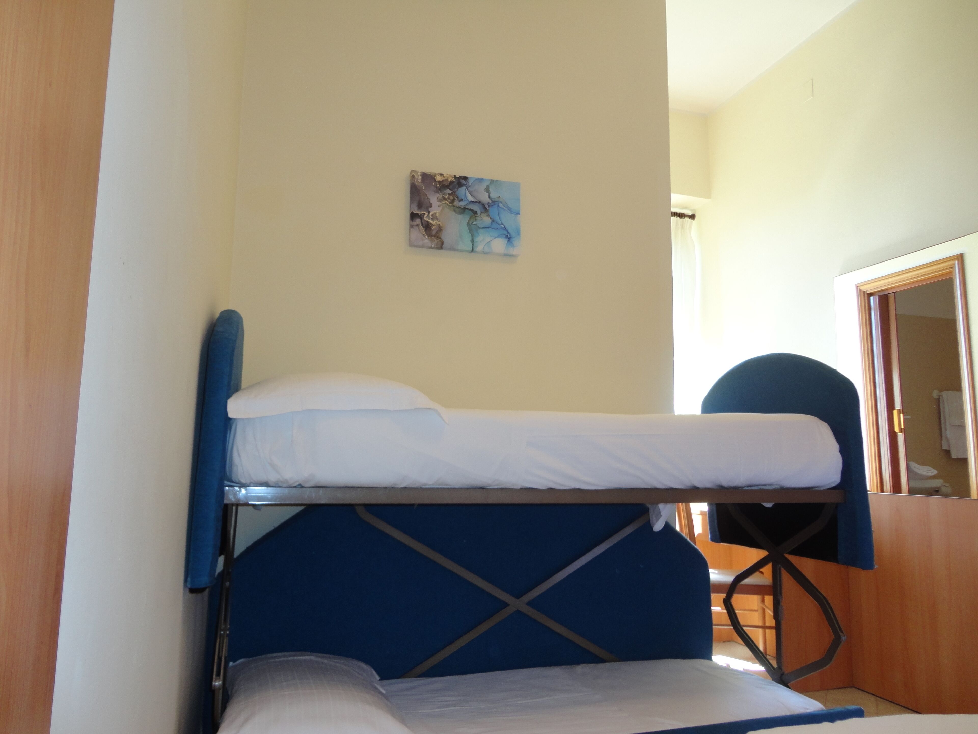 Uma cama beliche com cabeceira azul e roupa de cama branca.