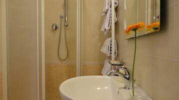 A bathroom with a white sink, a handheld showerhead, and a towel rack.