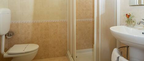 A bathroom with a toilet, a shower, and a sink.