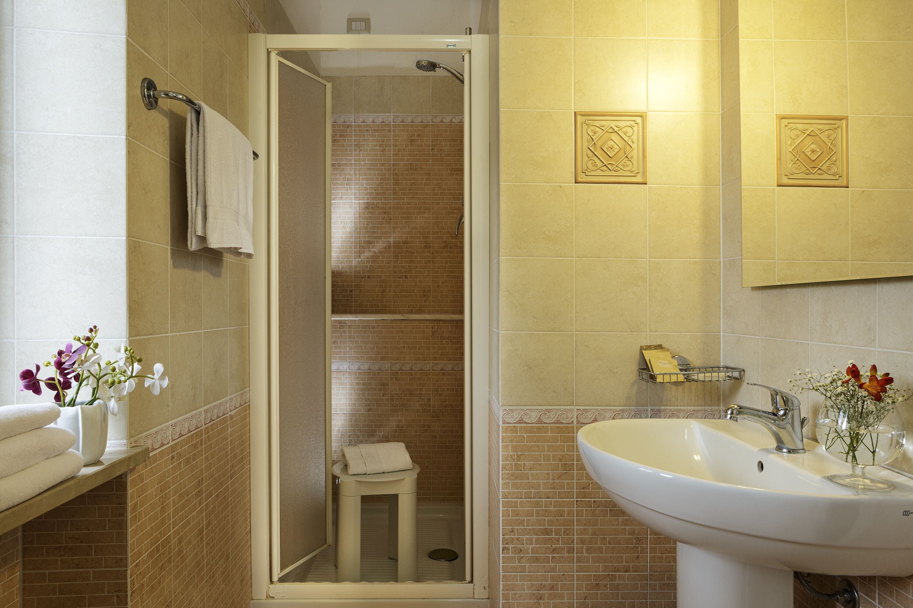 Un baño con ducha, lavabo y toallero.