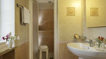 Un baño con ducha, lavabo y toallero.