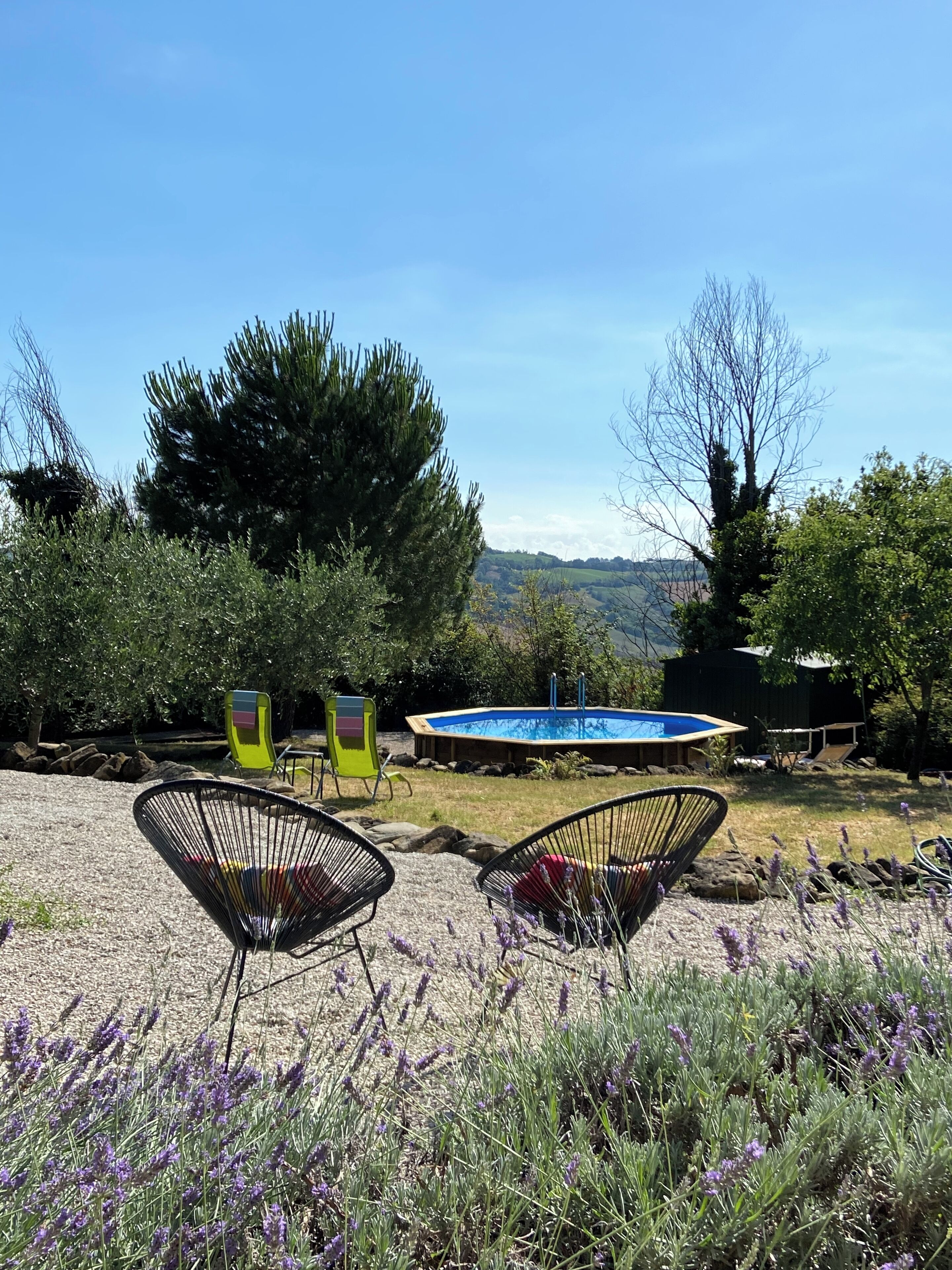 A backyard with a swimming pool, two chairs, and a view of hills.