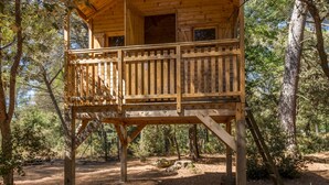 Una cabaña de madera con balcón, rodeada de árboles.