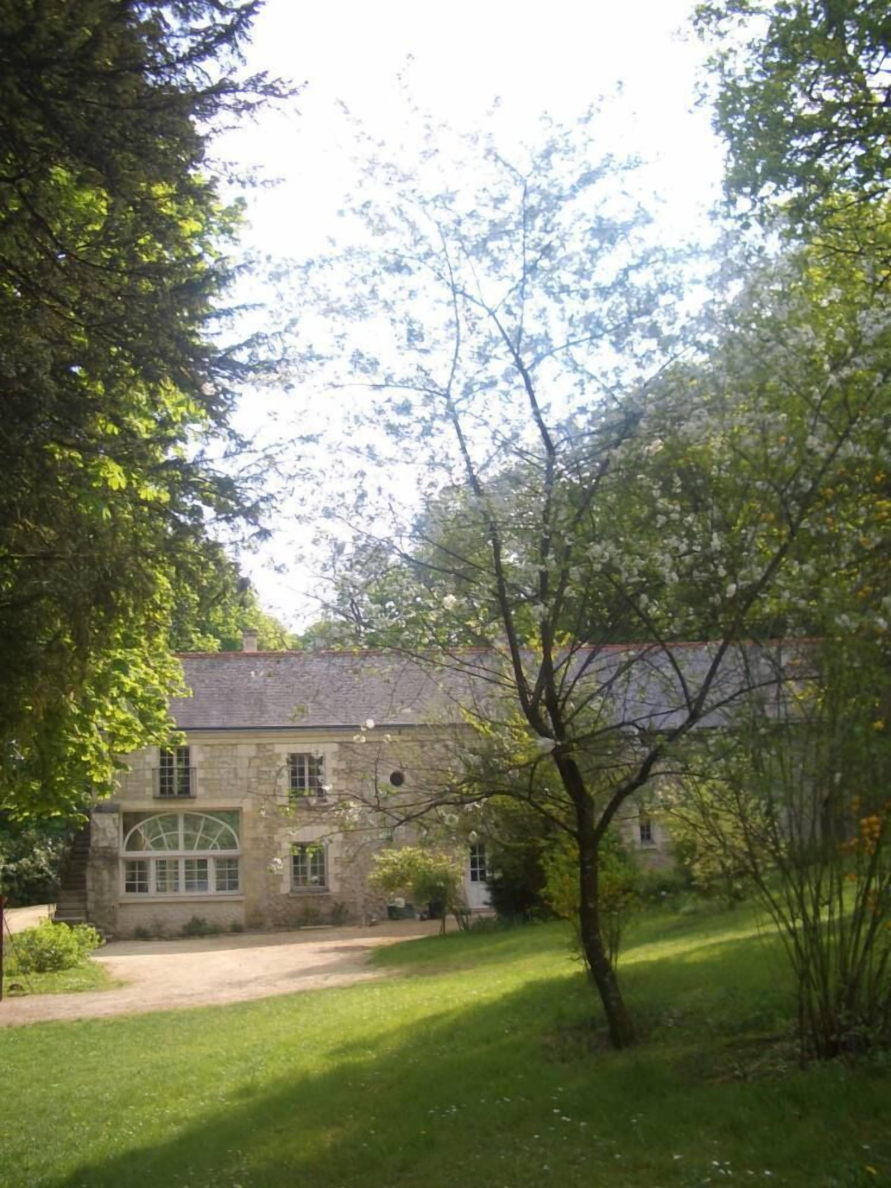 Un bâtiment en pierre doté d’une grande fenêtre et d’une pelouse devant.