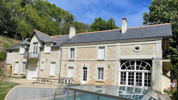 A large stone building with a swimming pool, a balcony, and a large arched window. - Large family house with pool in the heart of the Loire Valley (Langeais)