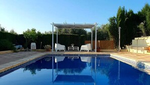 Une piscine dotée d’une pergola et de chaises longues.