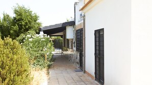 Un étroit sentier mène à un bâtiment à la façade blanche et à la porte noire.