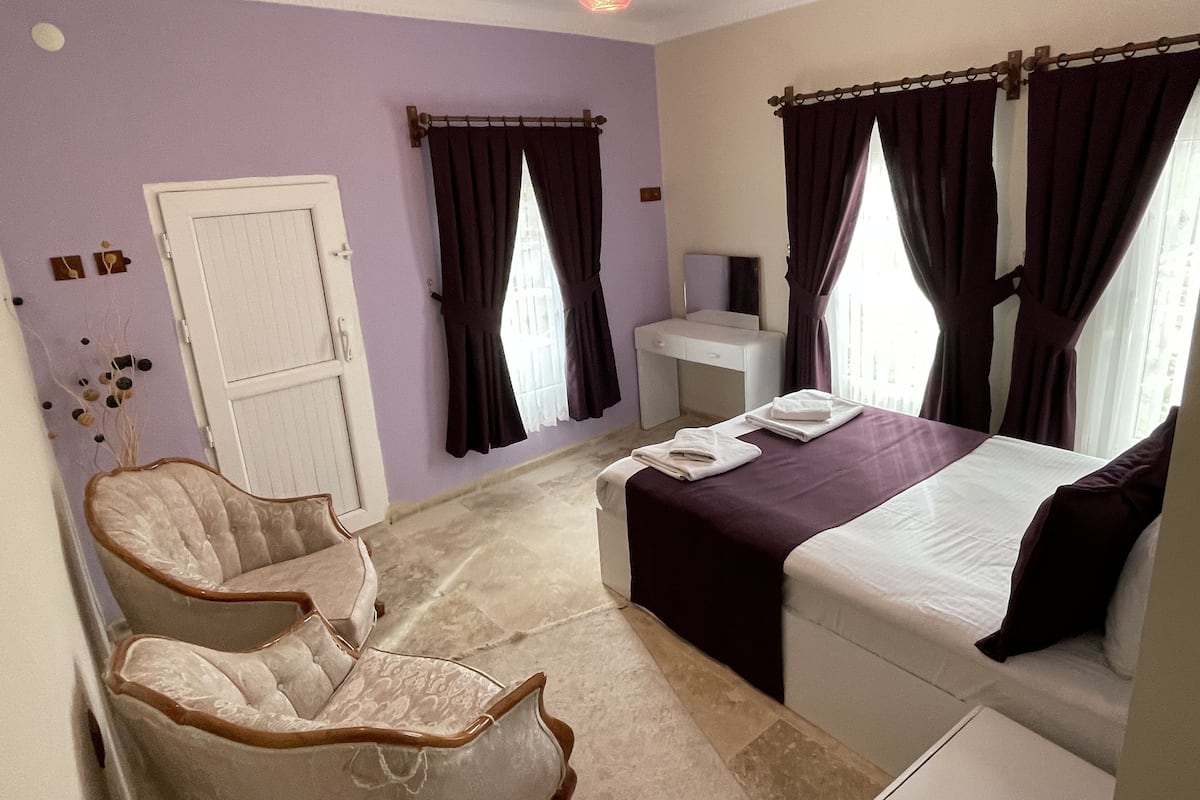 Habitación de hotel con cama, escritorio, silla y ventana con cortinas.