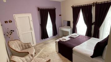 A hotel room with a bed, a desk, a chair, and a window with curtains.