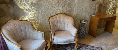 A room with two upholstered armchairs, a small wooden desk, and a patterned rug.