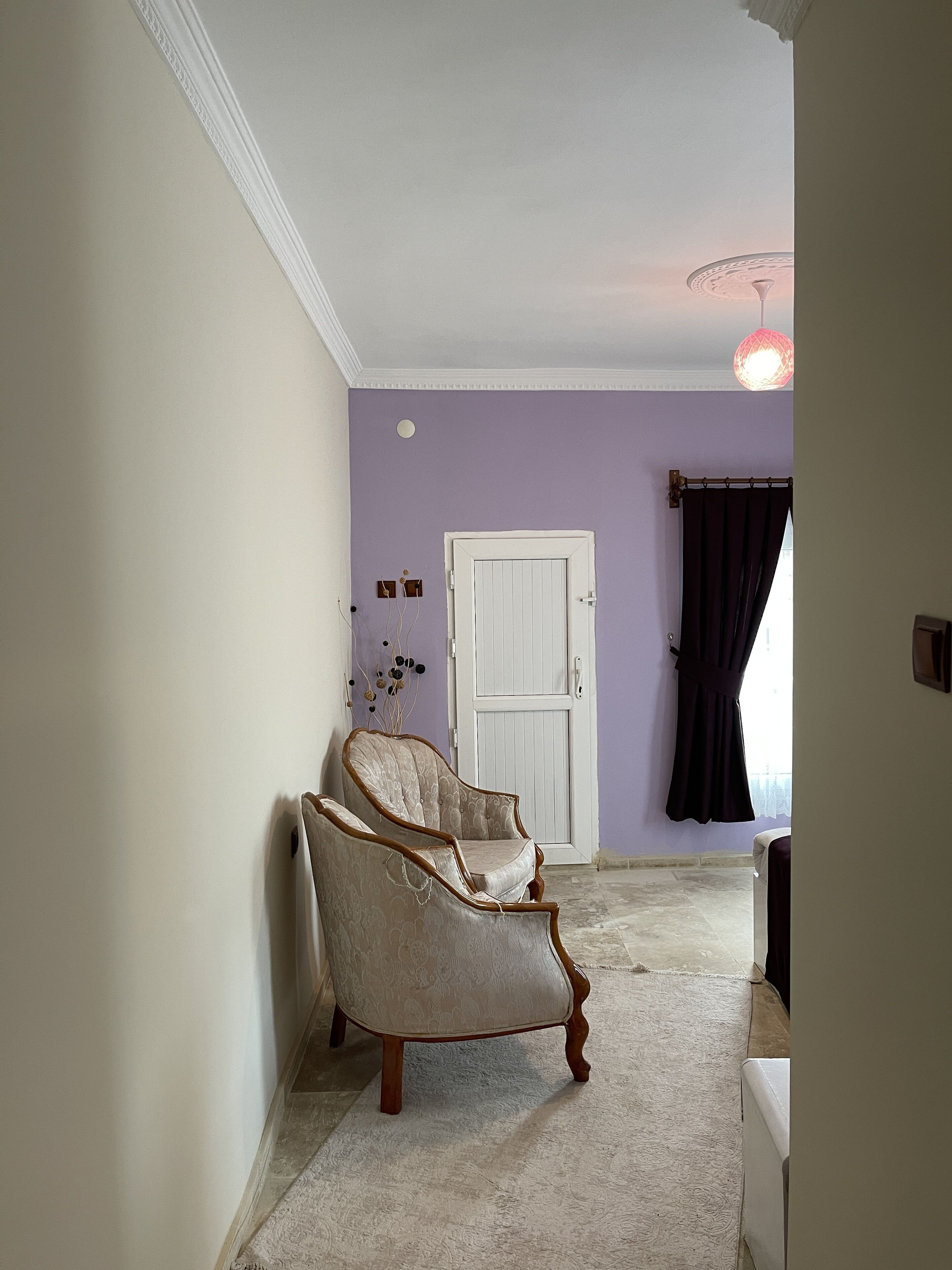A room with a white door, a dark curtain, and a patterned chair.