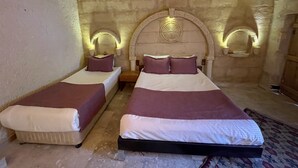 Una habitación con dos camas, cada una con cabecera y almohadas. La habitación tiene paredes de piedra y un techo decorativo.