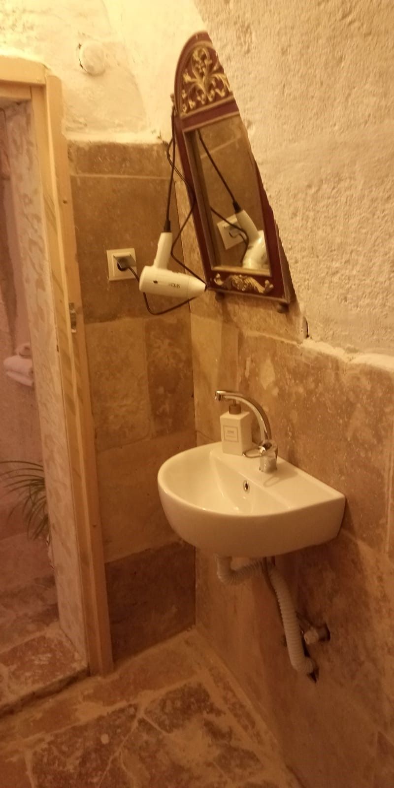 A bathroom with a white sink, a mirror, and a hairdryer plugged in.