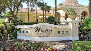 Un panneau indiquant l’emplacement du club-house de Windsor Hills, avec un jardin aménagé et des palmiers.