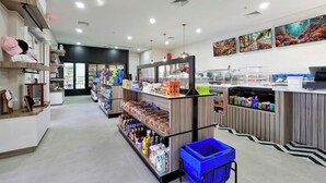 Une épicerie propre et bien éclairée, avec des étagères remplies de divers produits, un rayon réfrigéré et une zone de caisse.