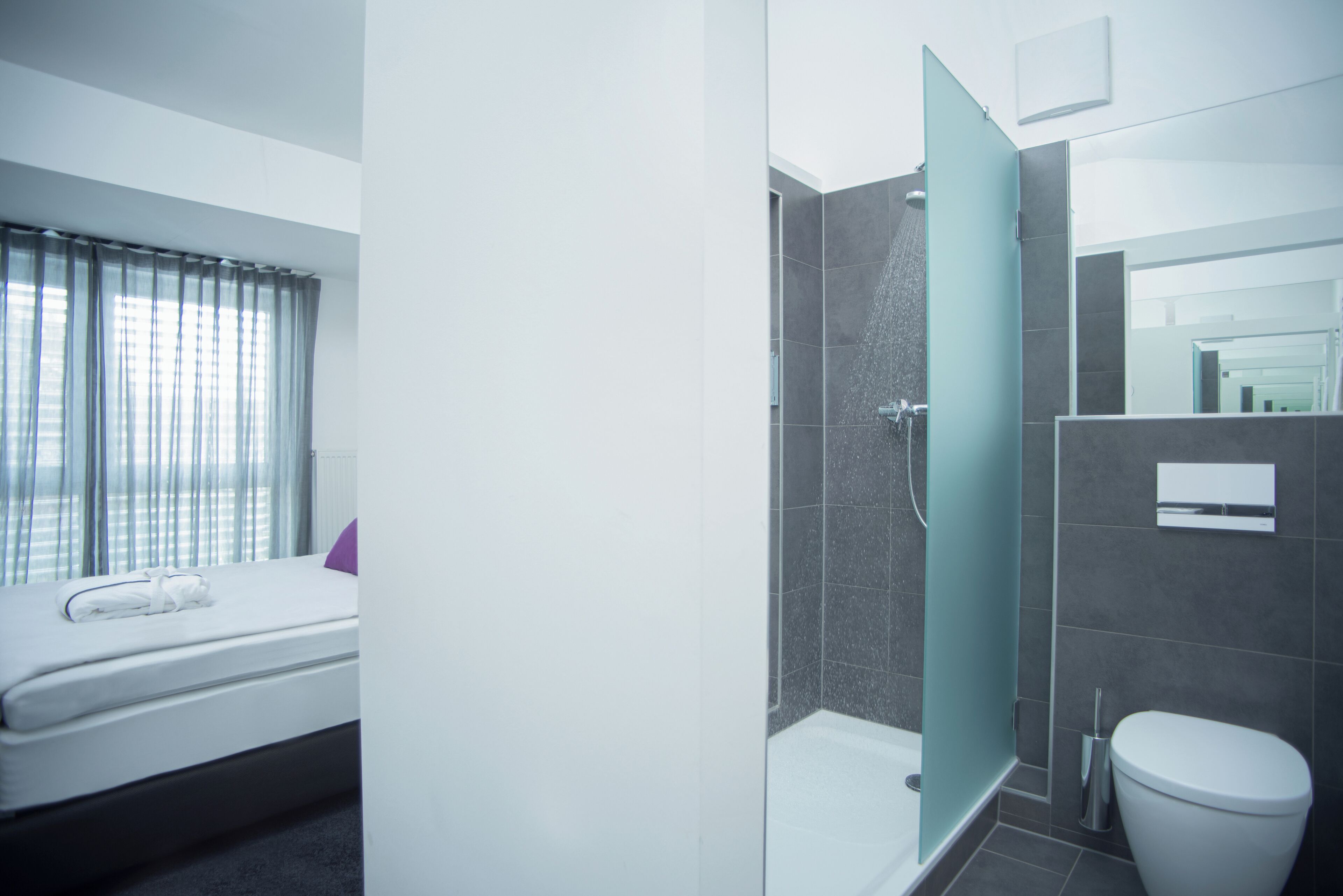 Un baño moderno con ducha, inodoro y cama con ventana.