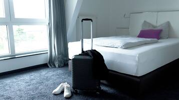 Ein Hotelzimmer mit einem Bett, einem Koffer und einem Paar Schuhe auf dem Boden.