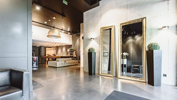 A modern lobby with a sofa, a reception desk, and a seating area with chairs. - &REPEAT Köln Airport (Cologne)