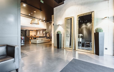 A modern lobby with a sofa, a reception desk, and a seating area with chairs.