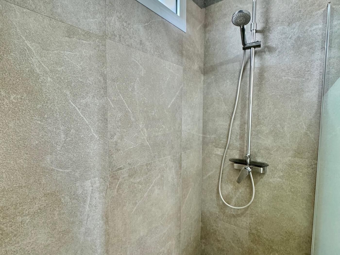 A shower with a handheld showerhead and a handheld hose.
