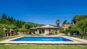 A pool with a thatched-roof structure, a lawn, and a building with a tiled roof. - Villa Roser Vell By SunVillas Mallorca (Pollença)