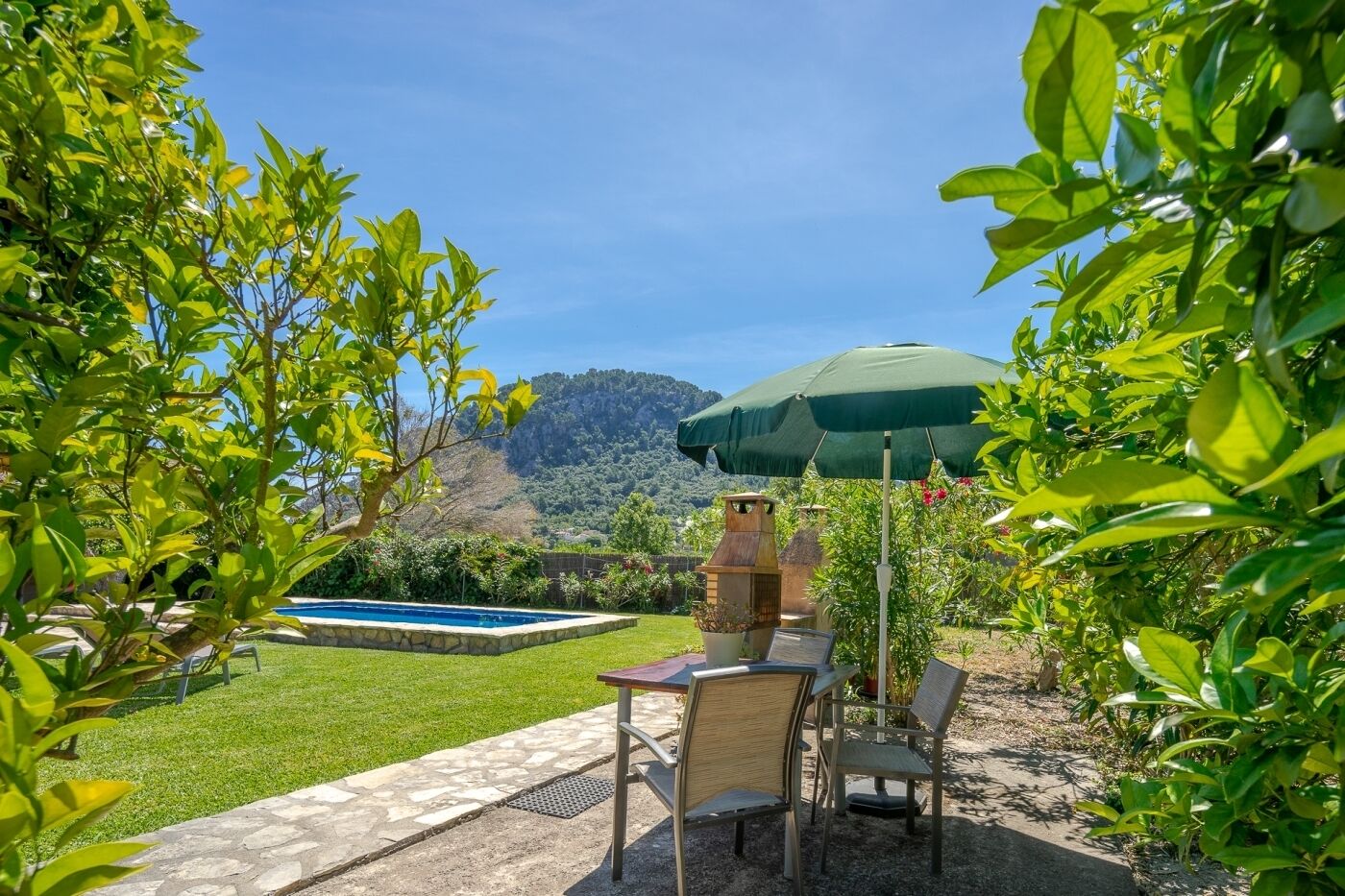Um pátio com mesa e cadeiras, uma piscina de pedra e vista para uma montanha.