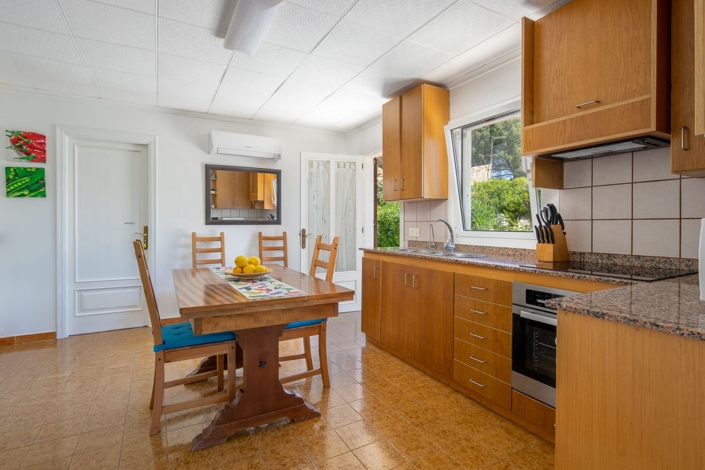 A kitchen with wooden cabinets, a granite countertop, and a dining table with chairs.