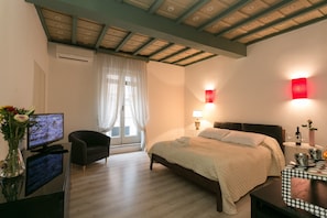 A hotel room with a bed, a TV, a chair, a desk, and a vase with flowers. - Parione House apartment in the center of Rome (Roma)
