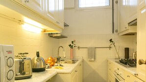 A compact kitchen with white cabinets, a checkered floor, a window, and basic appliances.